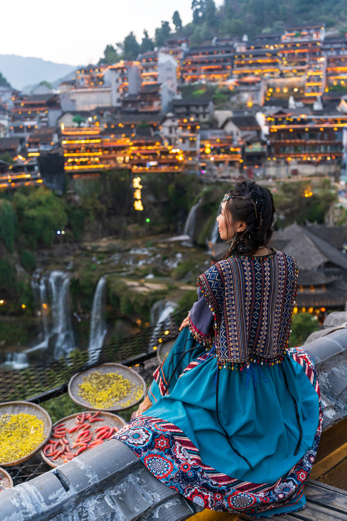 Mujer con ropa tradicional China admirando el paisaje de la Ciudad de Lijiand.